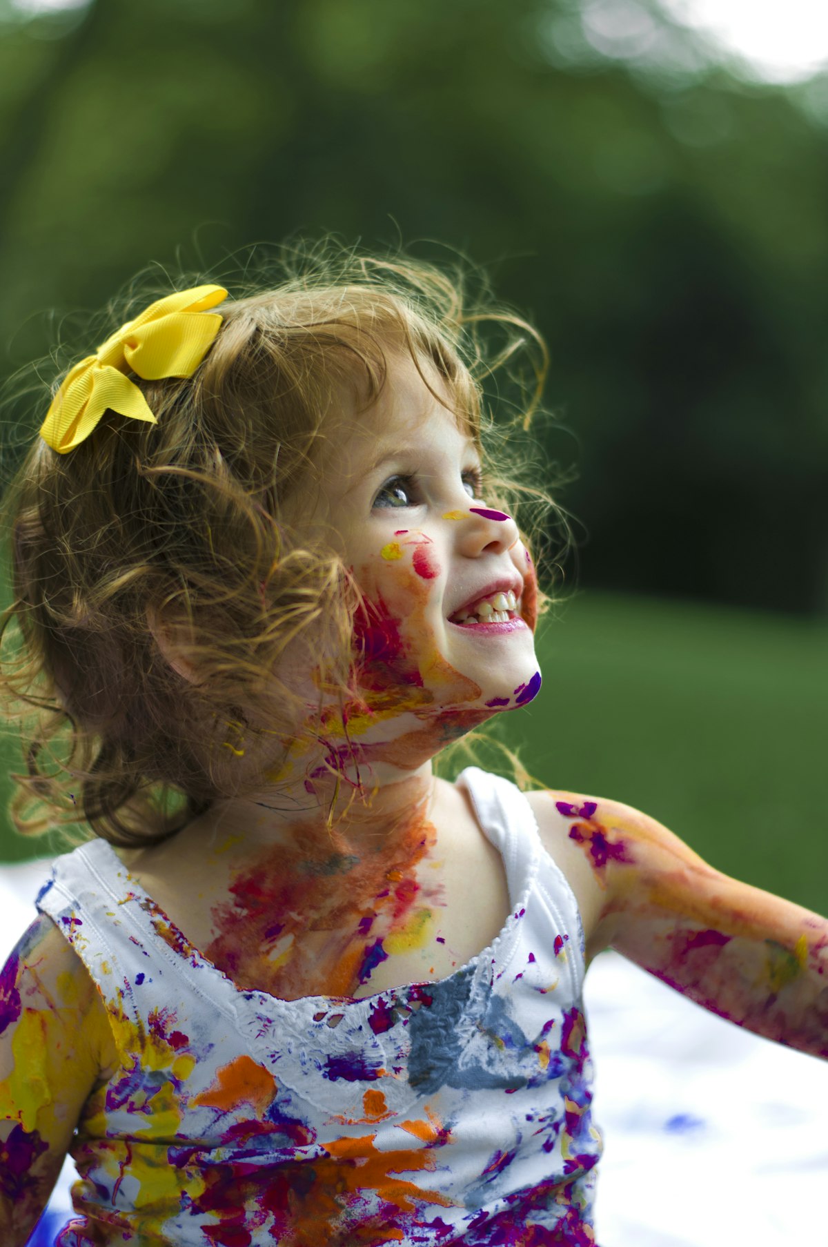 Toddler girl covered head-to-toe in finger paint, beaming — the aftermath of unsupervised creativity