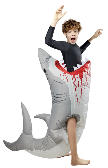 Boy with his arms up, apparently being eaten by a grey inflatable shark