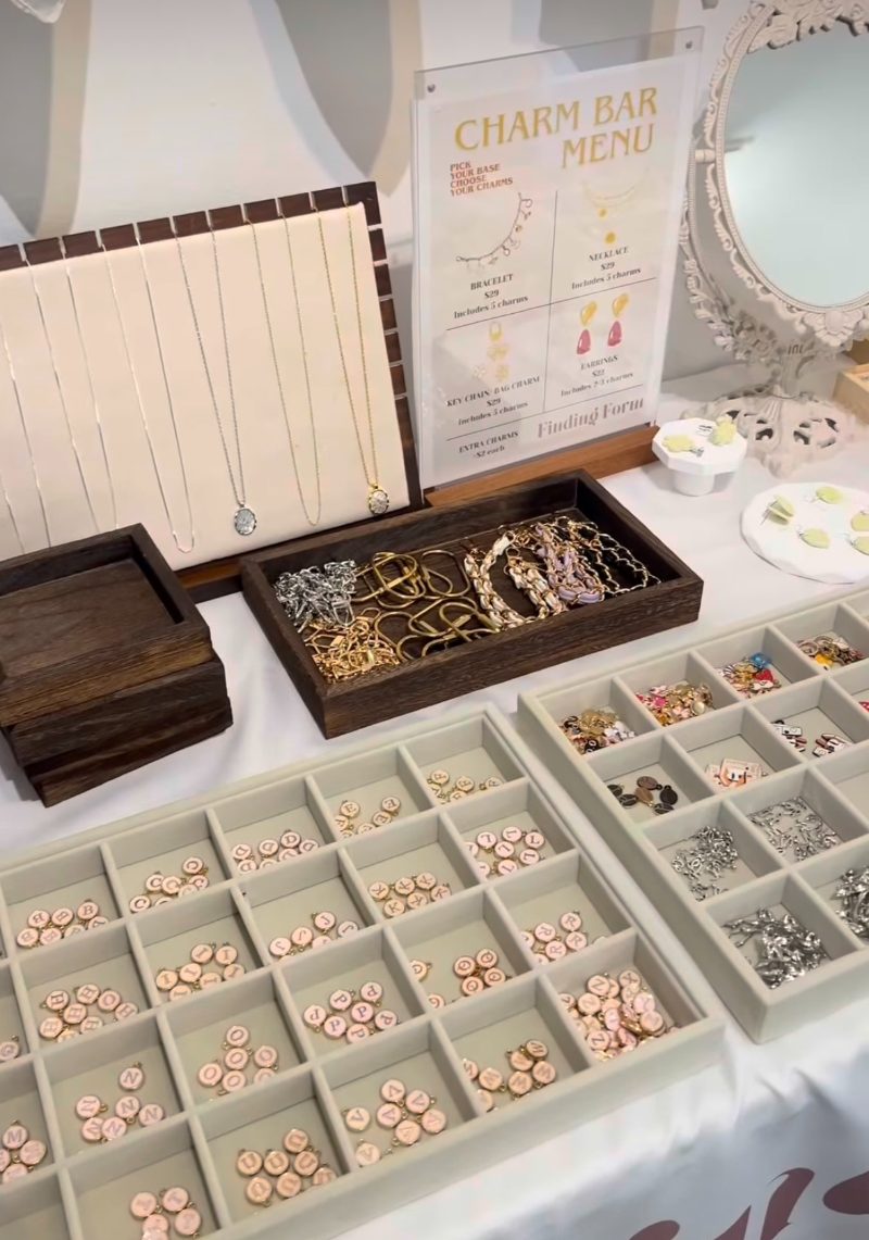 The Charm Bar menu on a table of necklaces, charm trays and bracelet chains at Finding Form