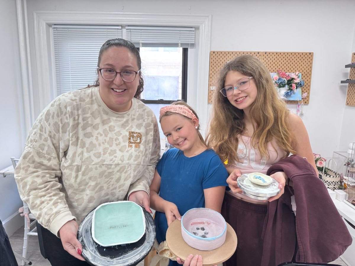 A woman and two girls smiling and holding hand-built clay bowls at Finding Form studio